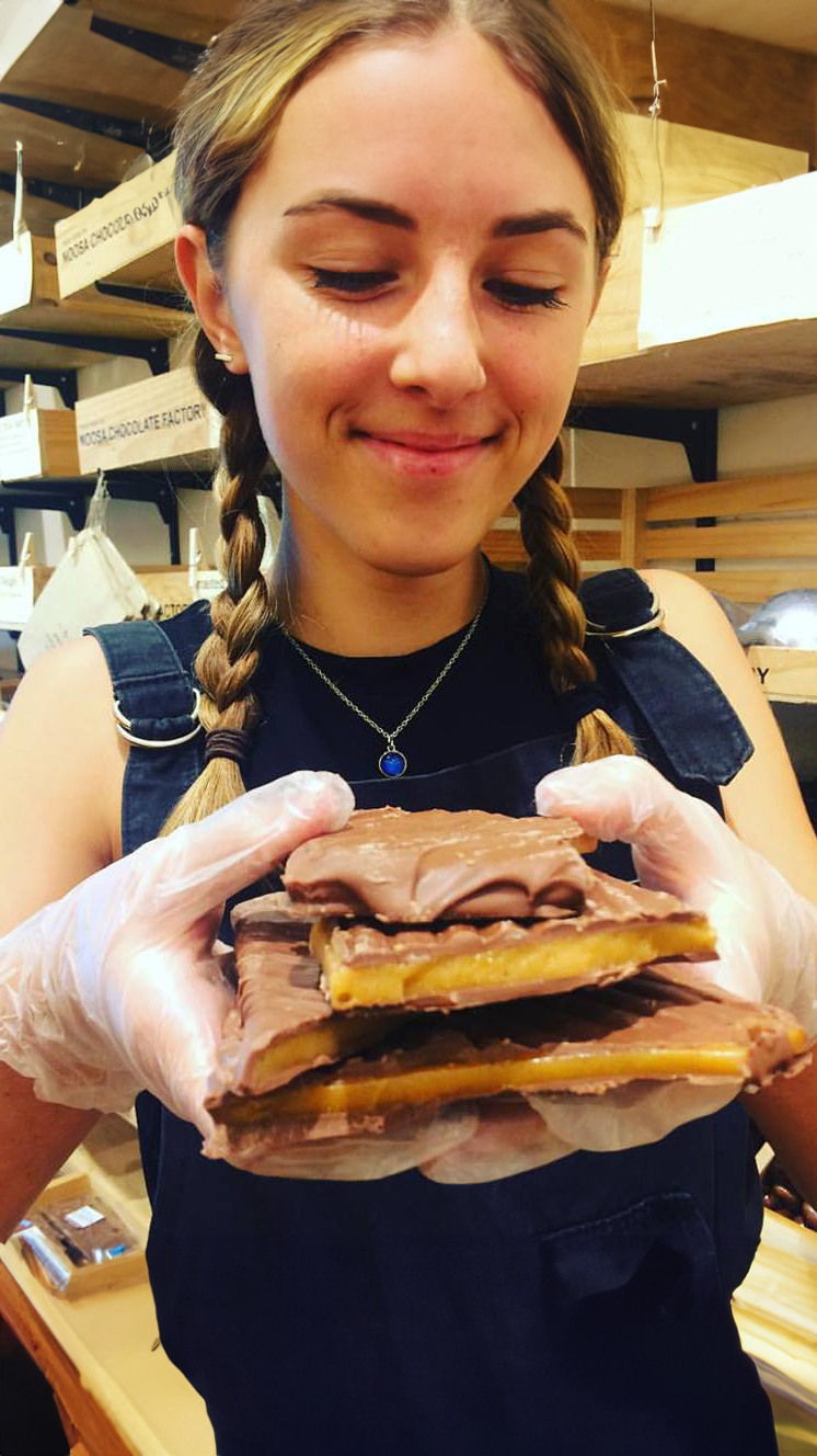 Noosa Staff Member Holds Chocolate Toffee Brittle Product